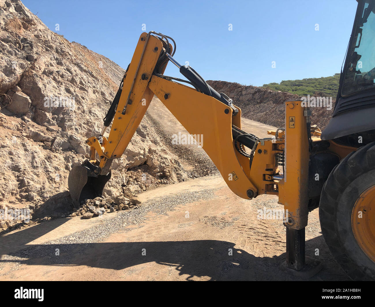 Yellow loader backhoe digs a trench during road construction works