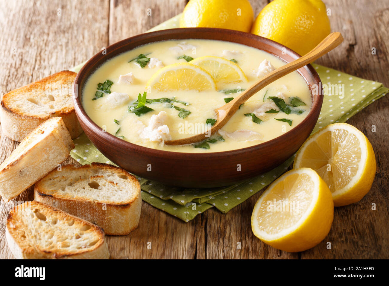 Classic Mediterranean lemon soup with chicken close-up in a bowl with bread on the table. horizontal Stock Photo