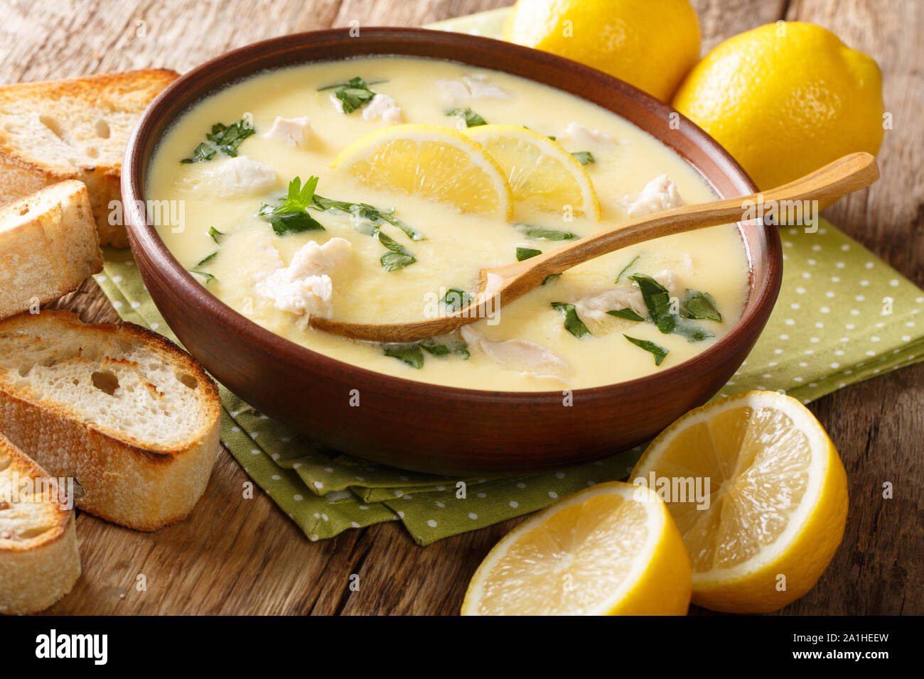Hot greek lemon soup with chicken close-up in a bowl with bread on the table. horizontal Stock Photo