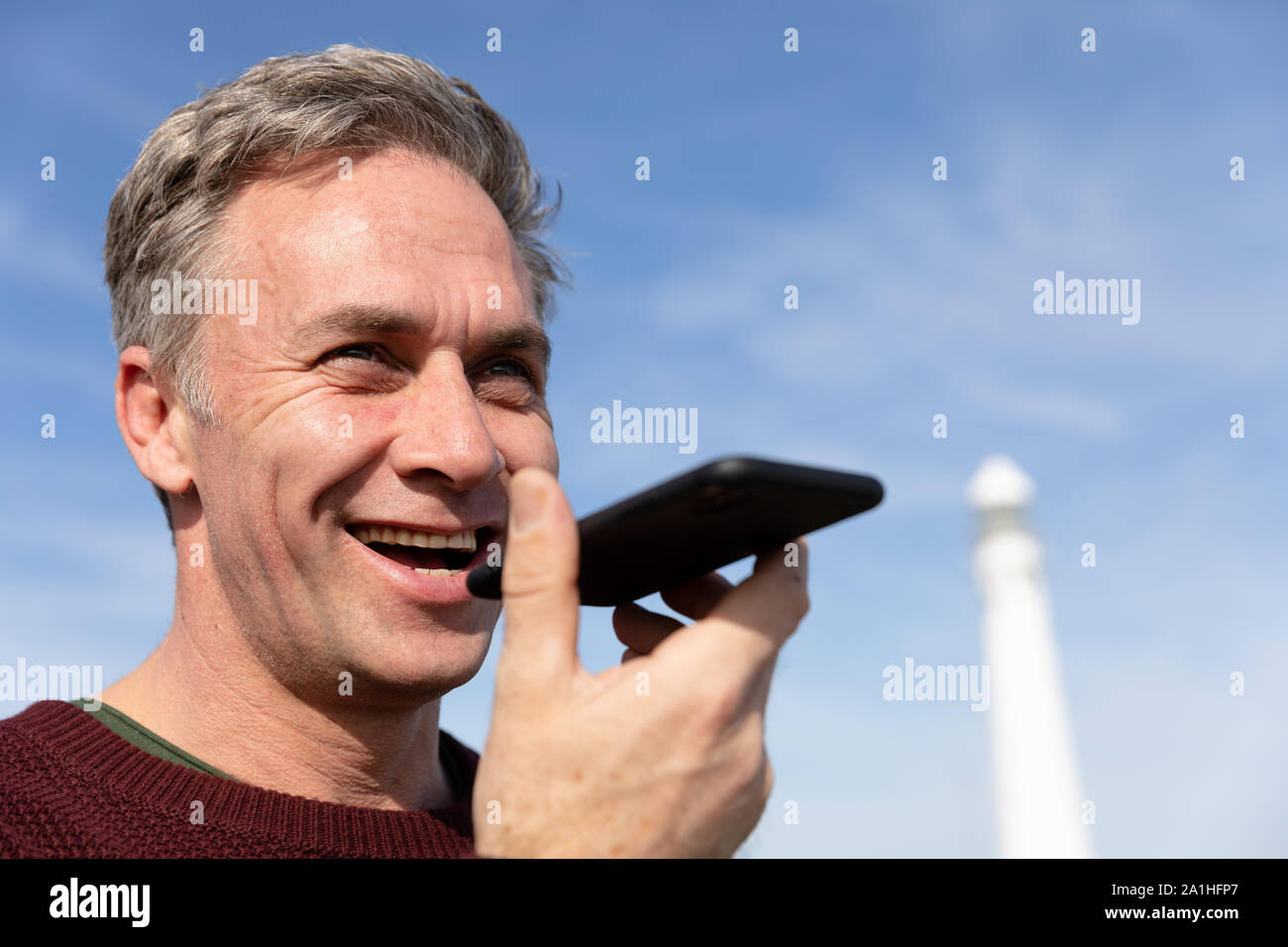 Man standing near lighthouse using smartphone Stock Photo