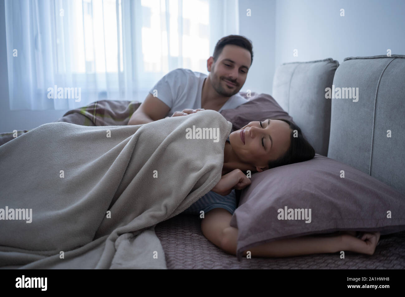 Young couple is lying in bed and waking up in the morning. Stock Photo