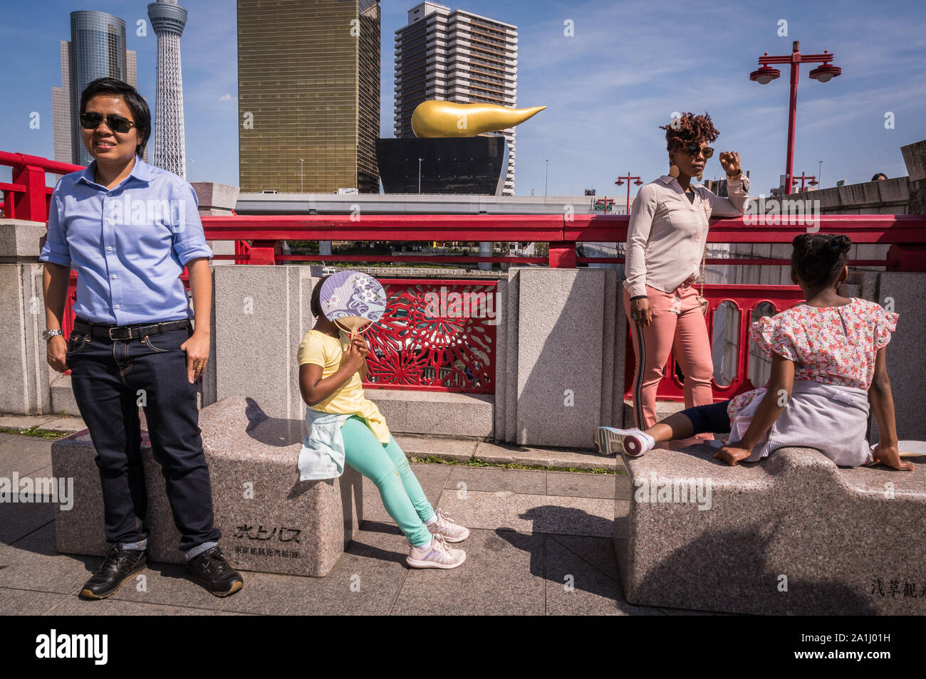 Tourists posing near Ueno Station with the Asahi Flame in the background, Tokyo, Japan Stock Photo
