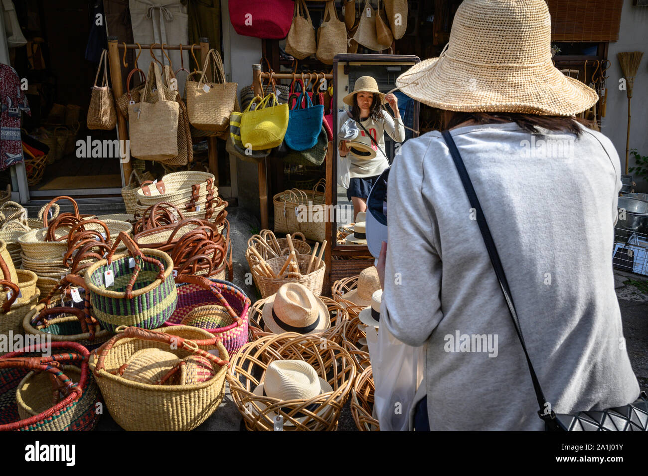 A young woman trying on hats, Yanaka Ginza, Tokyo, Japan Stock Photo