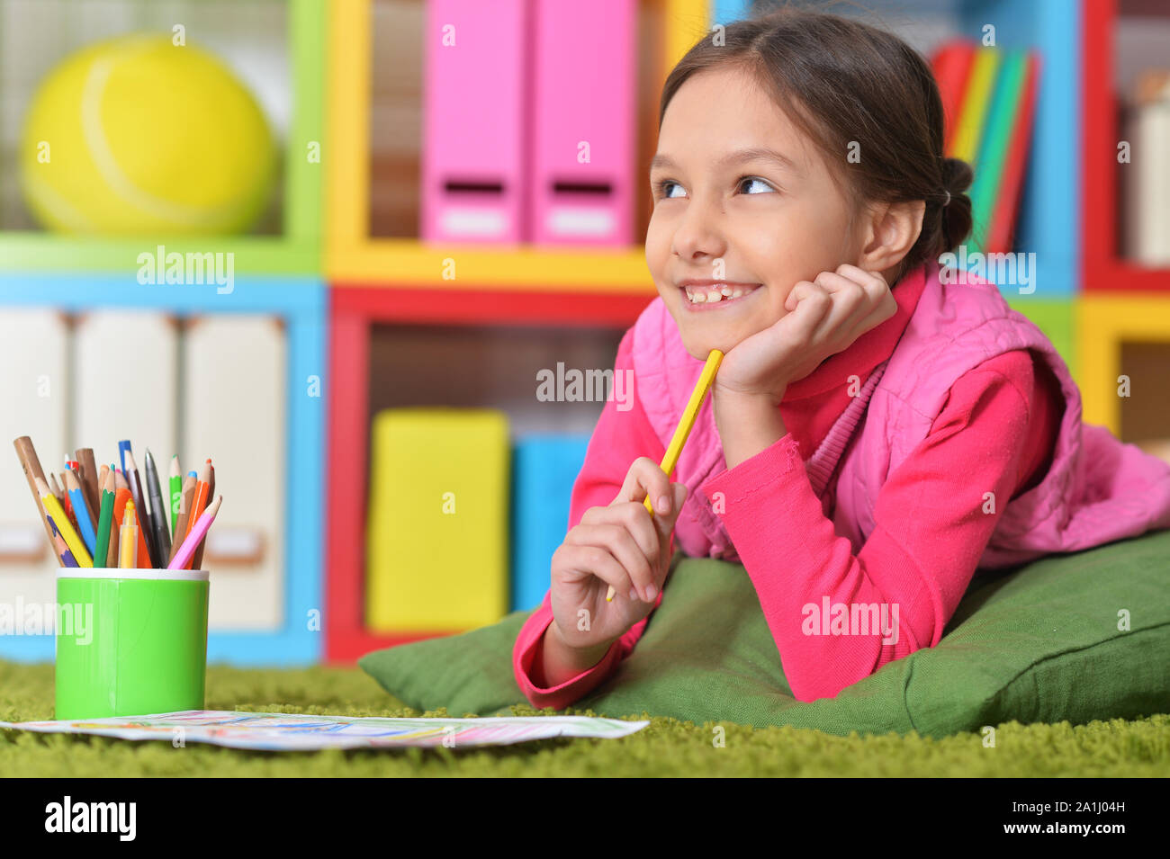 Cute little girl lying on floor and drawing Stock Photo - Alamy