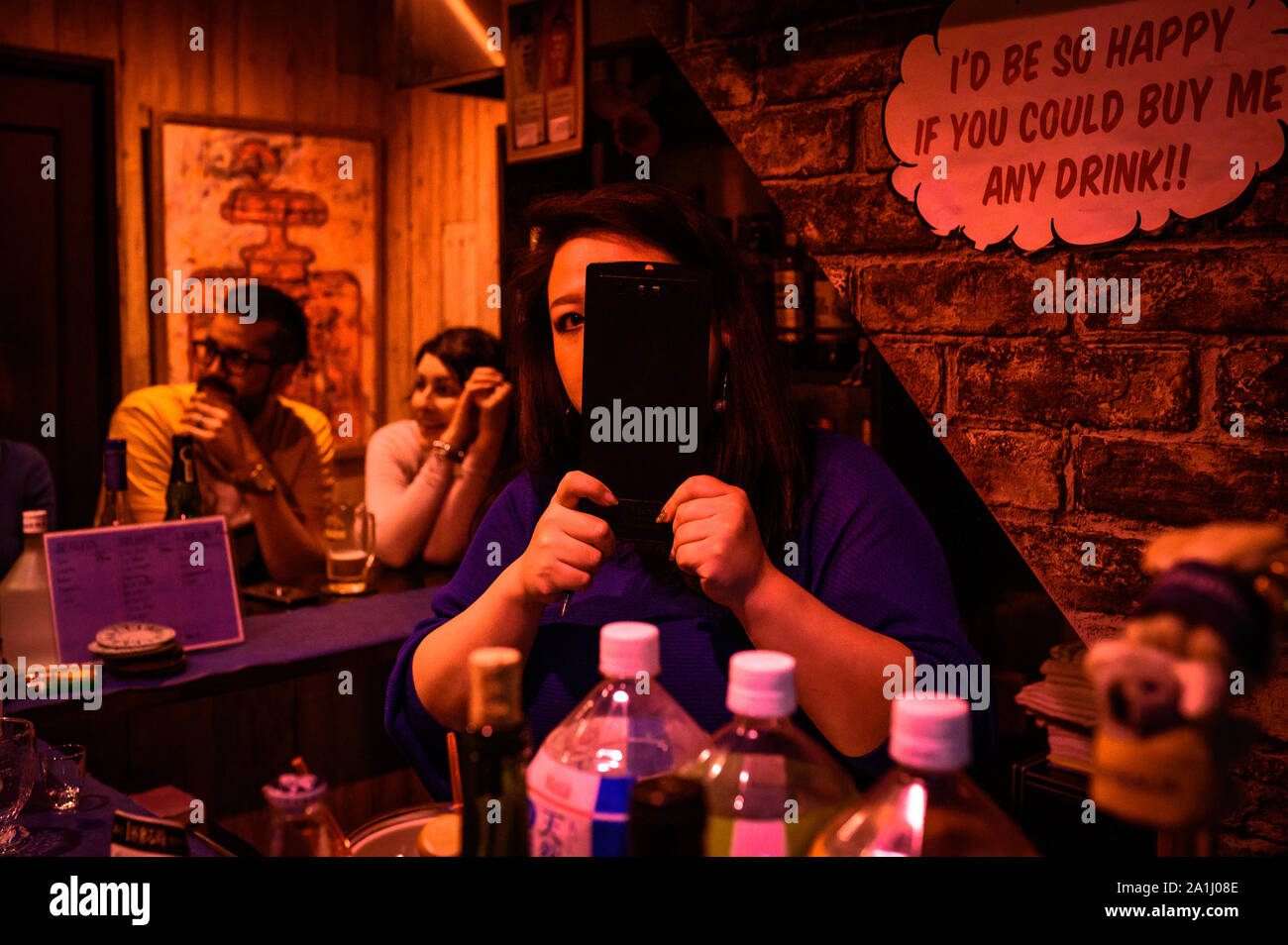 A woman and some customers inside of a small bar in Golden Gai, Shinjuku, Tokyo, Japan Stock Photo