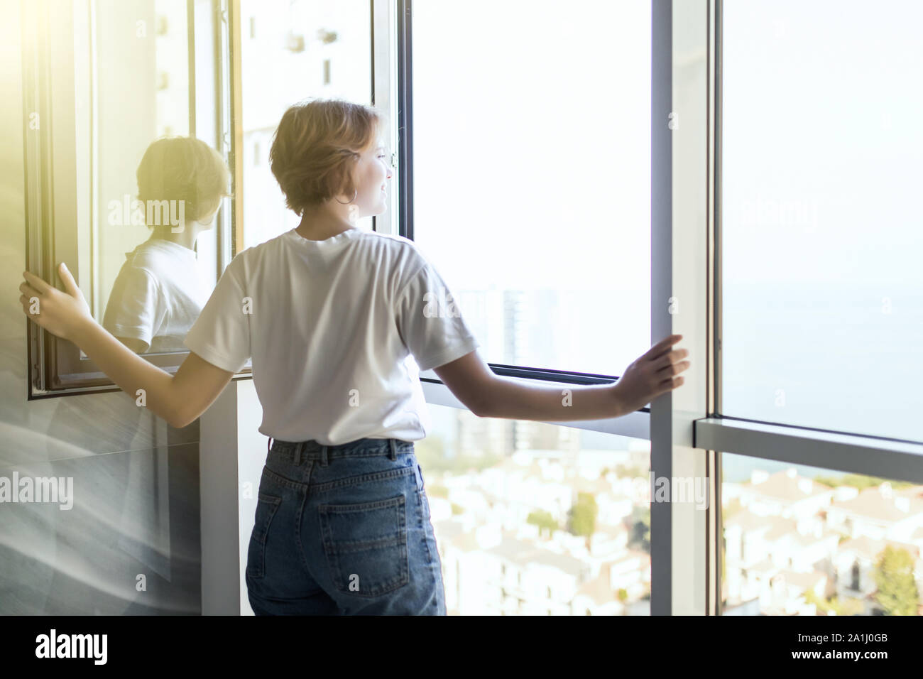 Young woman opening window in living room Stock Photo - Alamy