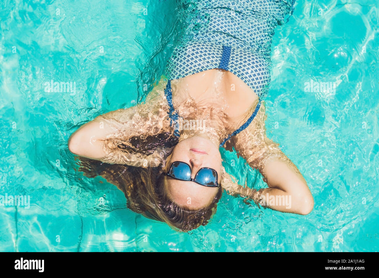 Beautiful young woman floating in pool relaxing Top view. Holiday ...