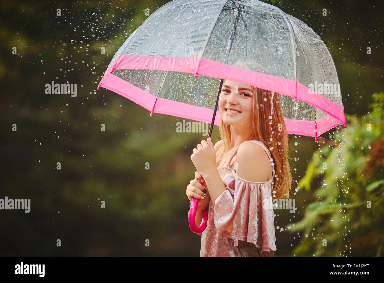 Happy beautiful girl with an umbrella in the rain during a forest ...