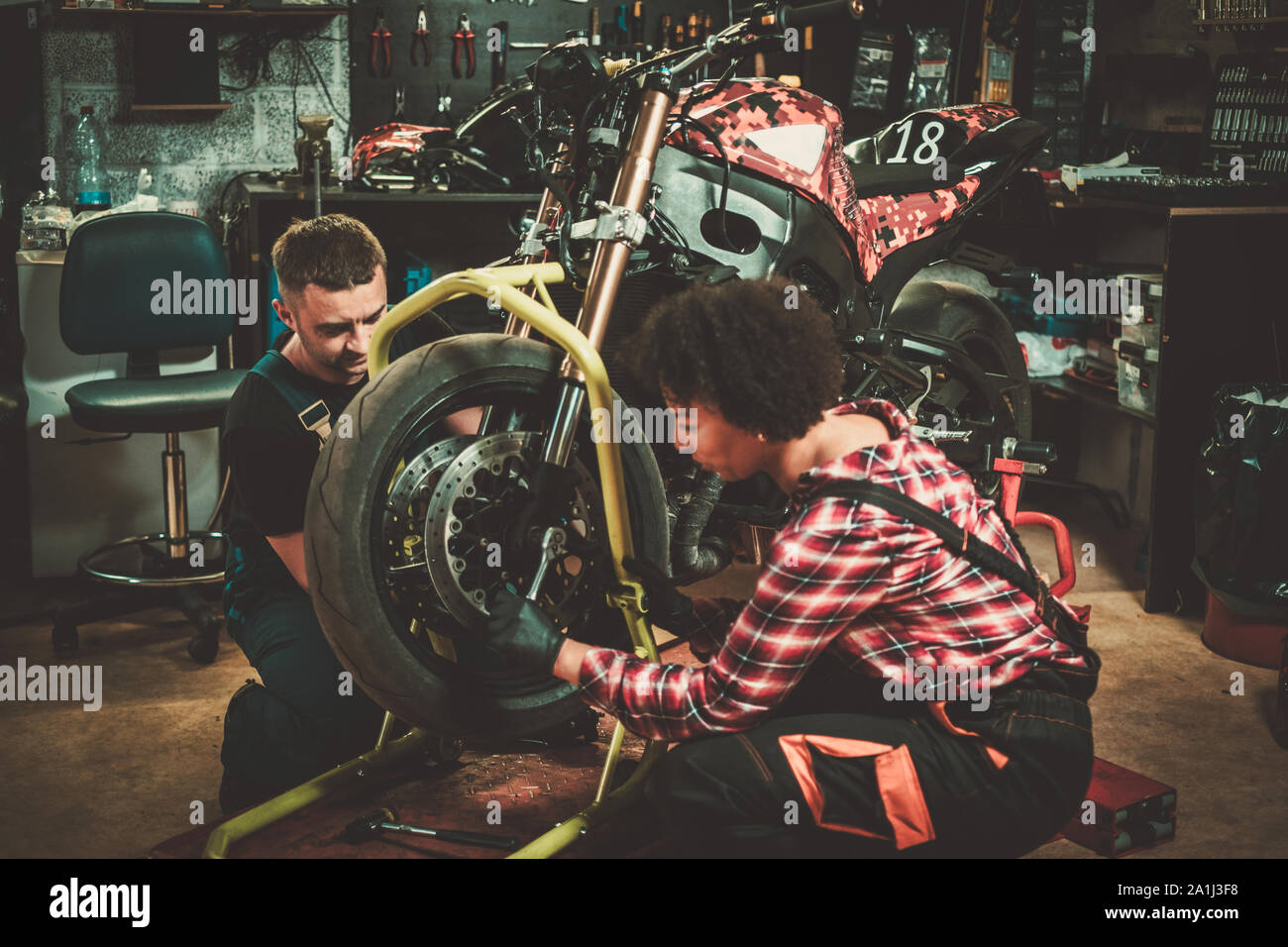 Mechanic and his helper repairing a motorcycle in a workshop Stock Photo