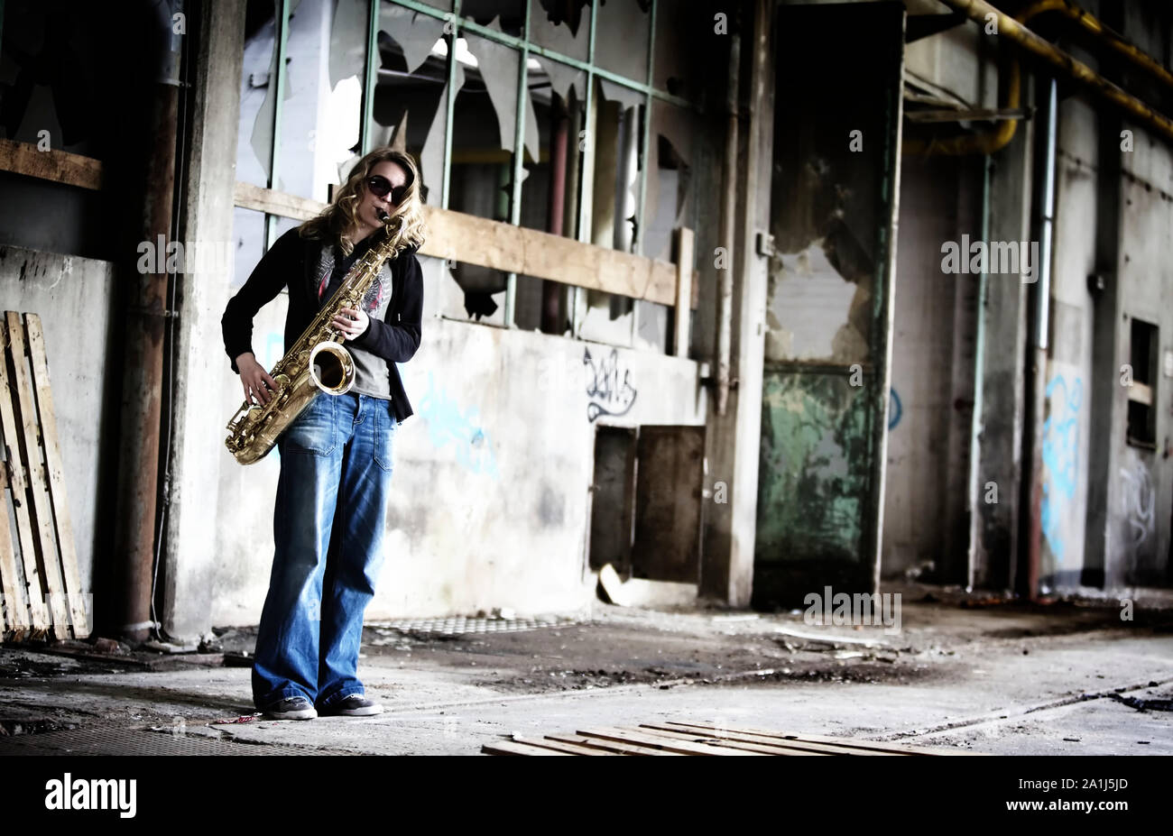 Girl playing saxophone in old factory hall. Stock Photo