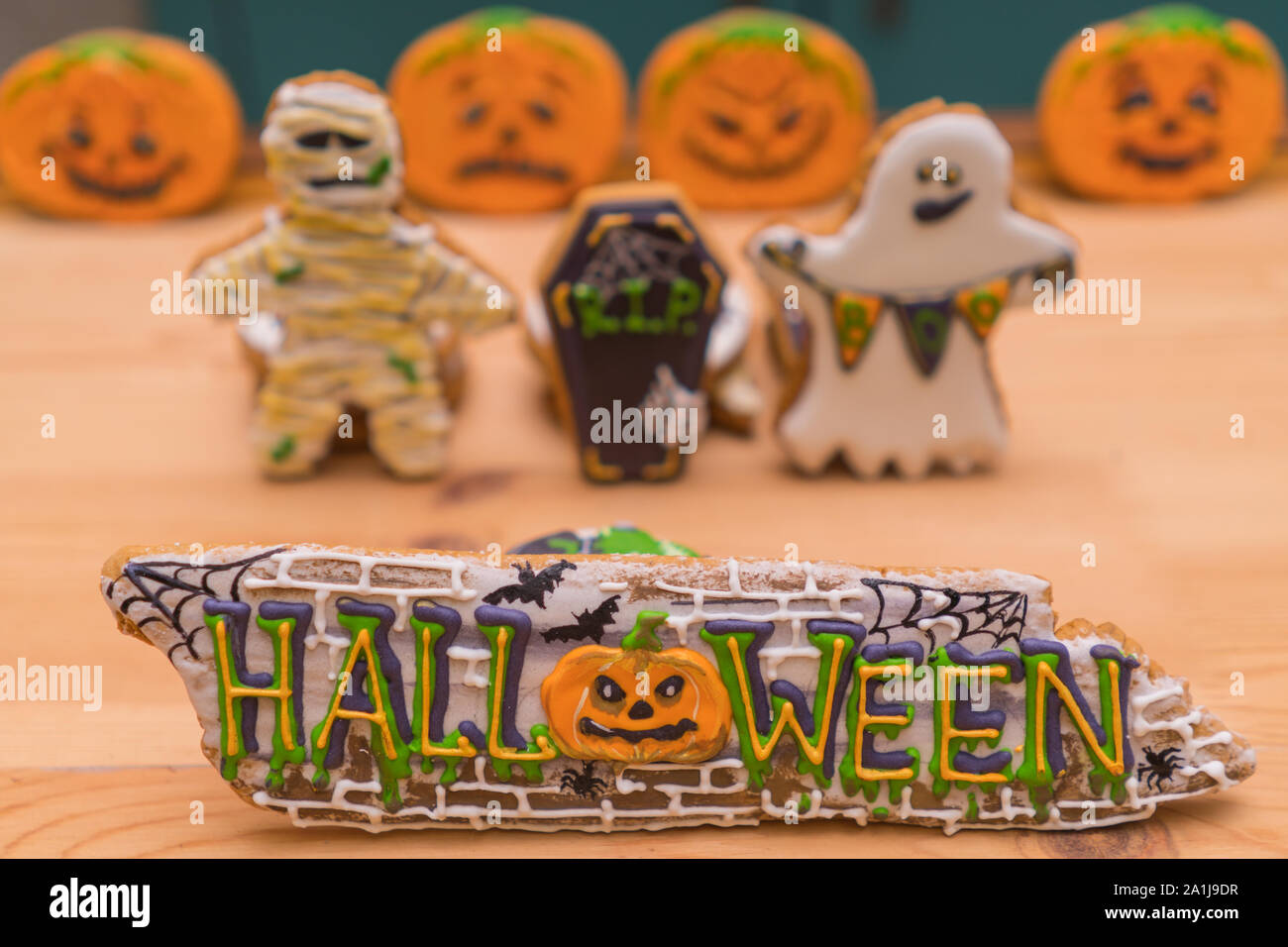 Halloween decals on gingerbreads and ghosts in the background in unfocus. Preparing for a Halloween party. Festive table Stock Photo