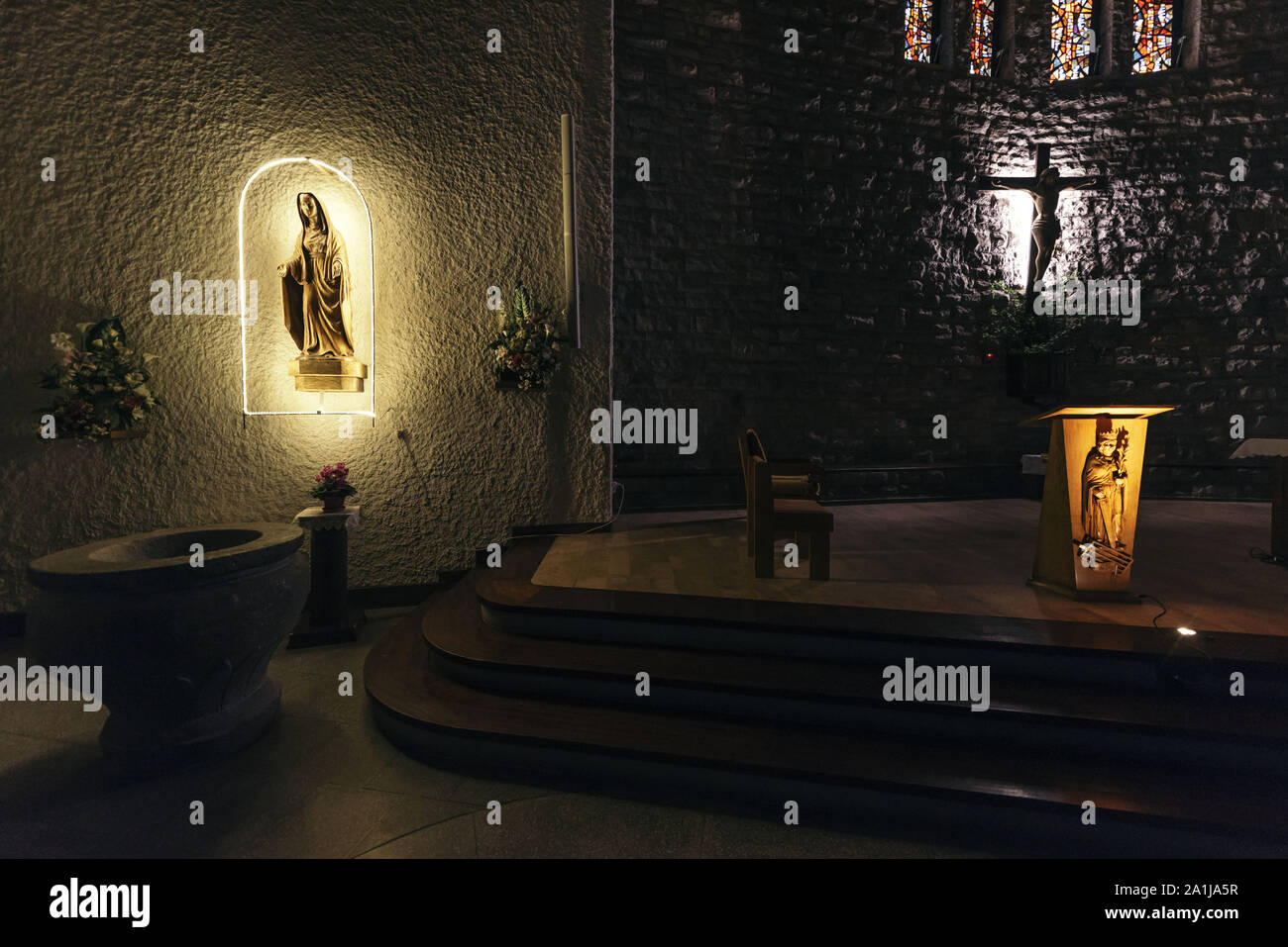 La Clusaz (eastern France). 2019/01/16: Statue of the Virgin illuminated in a niche, Christ on the Cross and altar in the church of the village Stock Photo