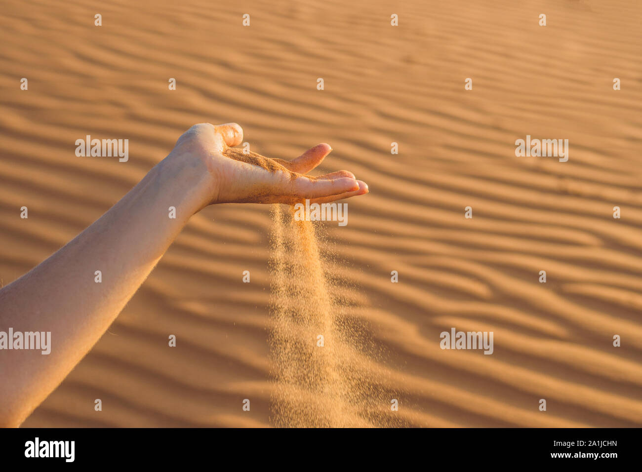 Sand slipping through the fingers of a woman's hand in the desert Stock