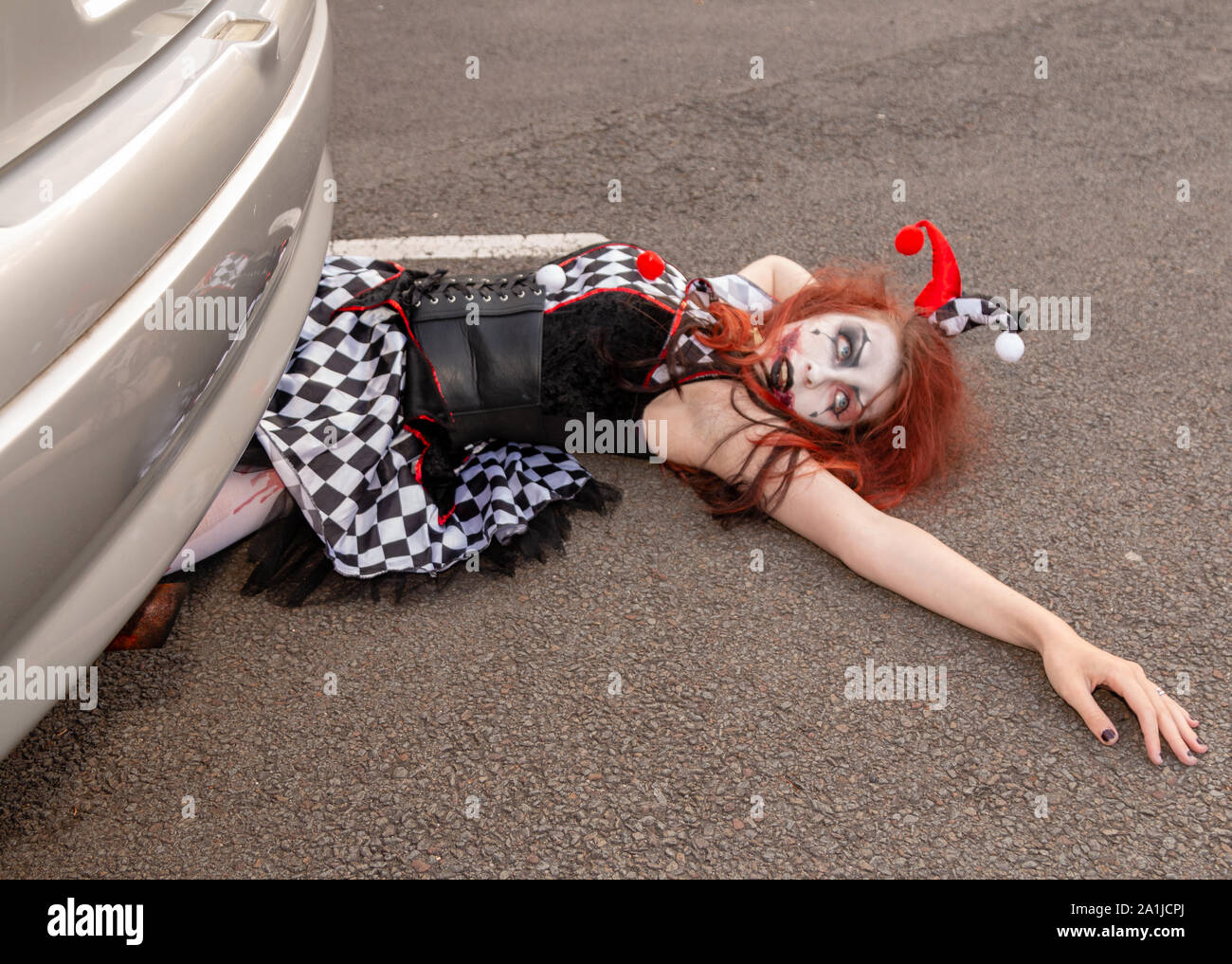 Young female in Harlequin costume lies covered in blood following car  accident Stock Photo - Alamy