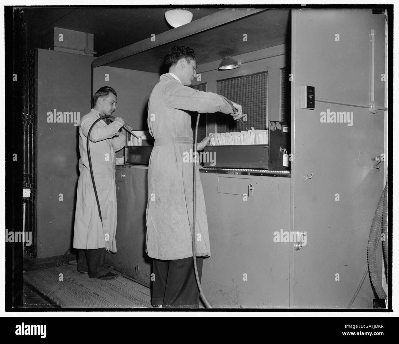 National Archives. Washington, D.C., Nov. 22. After leaving the gas chamber the documents are worked on by air blowers to eliminate all dust and foreign particles. The dust from the papers is carried out through the screen in the background into a purifier Stock Photo