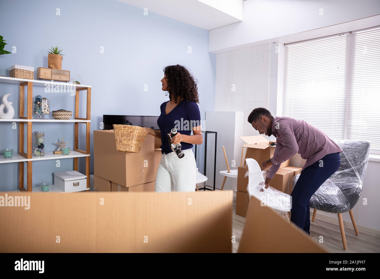 Couple Unpacking Boxes In Living Room In Their New Home Stock Photo
