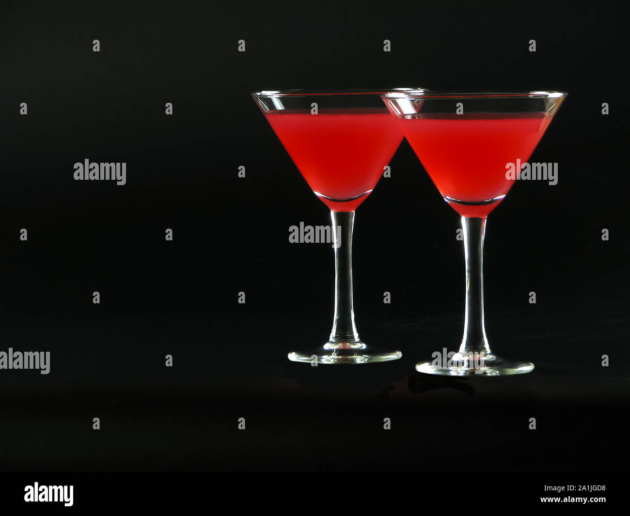 Classic Bacardi alcoholic cocktail of bright red color from white rum, lime juice and grenadine, in two conical cocktail glass on a dark background Stock Photo
