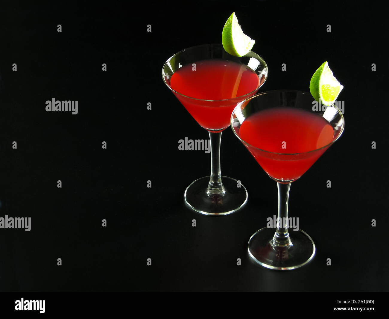 Two bright red Bacardi alcoholic cocktails made of white rum, lime juice and grenadine, in conical cocktail glasses, decorated with lime slices Stock Photo