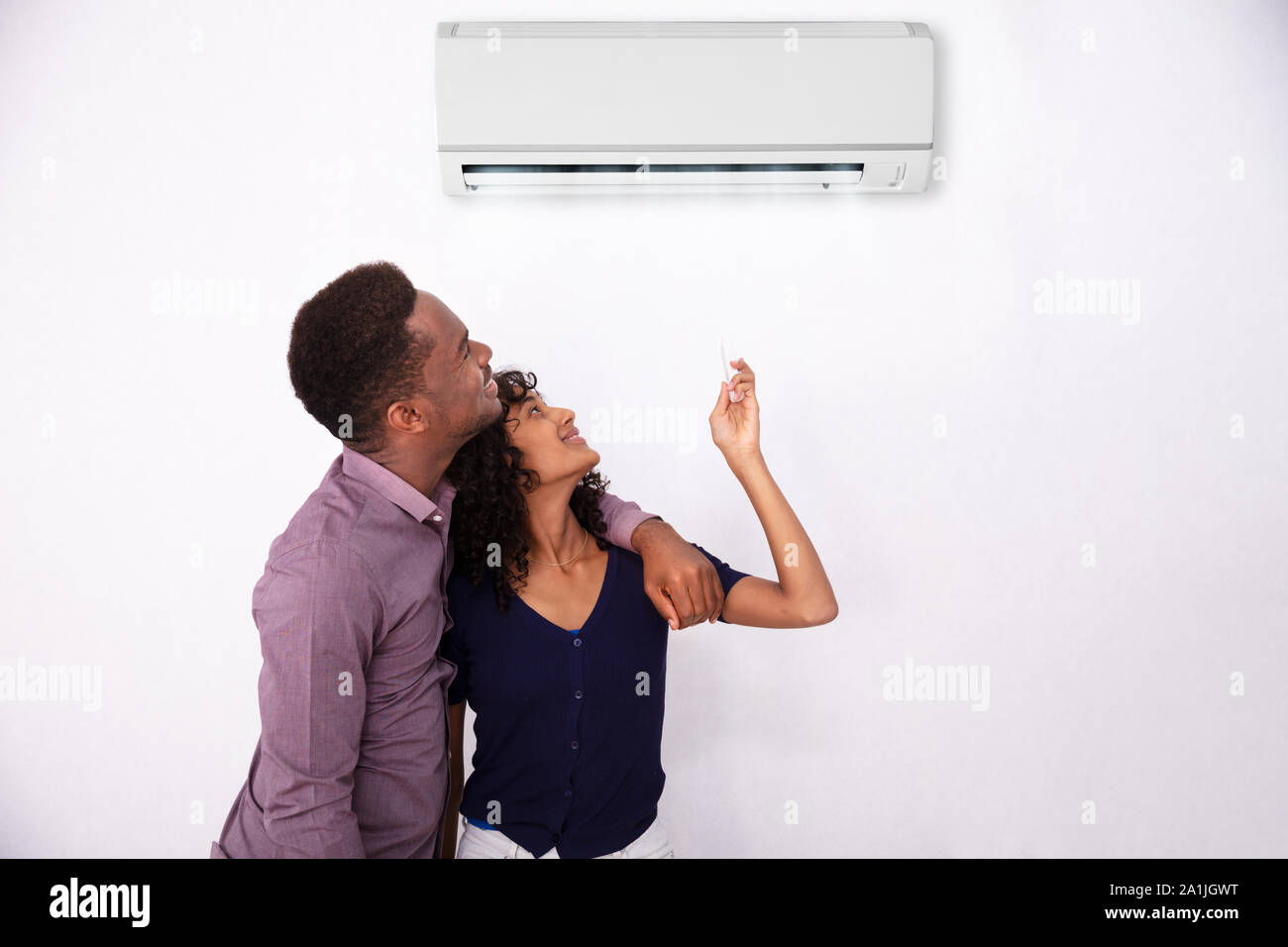 Couple Adjusting Temperature Of Air Conditioner At Home Stock Photo Alamy