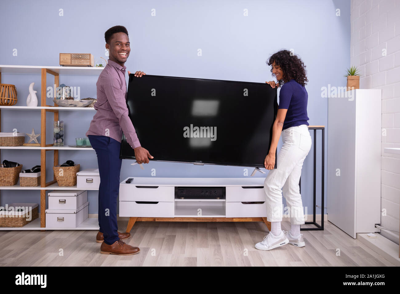 Side View Of Young Couple Lifting Television At Home Stock Photo Alamy