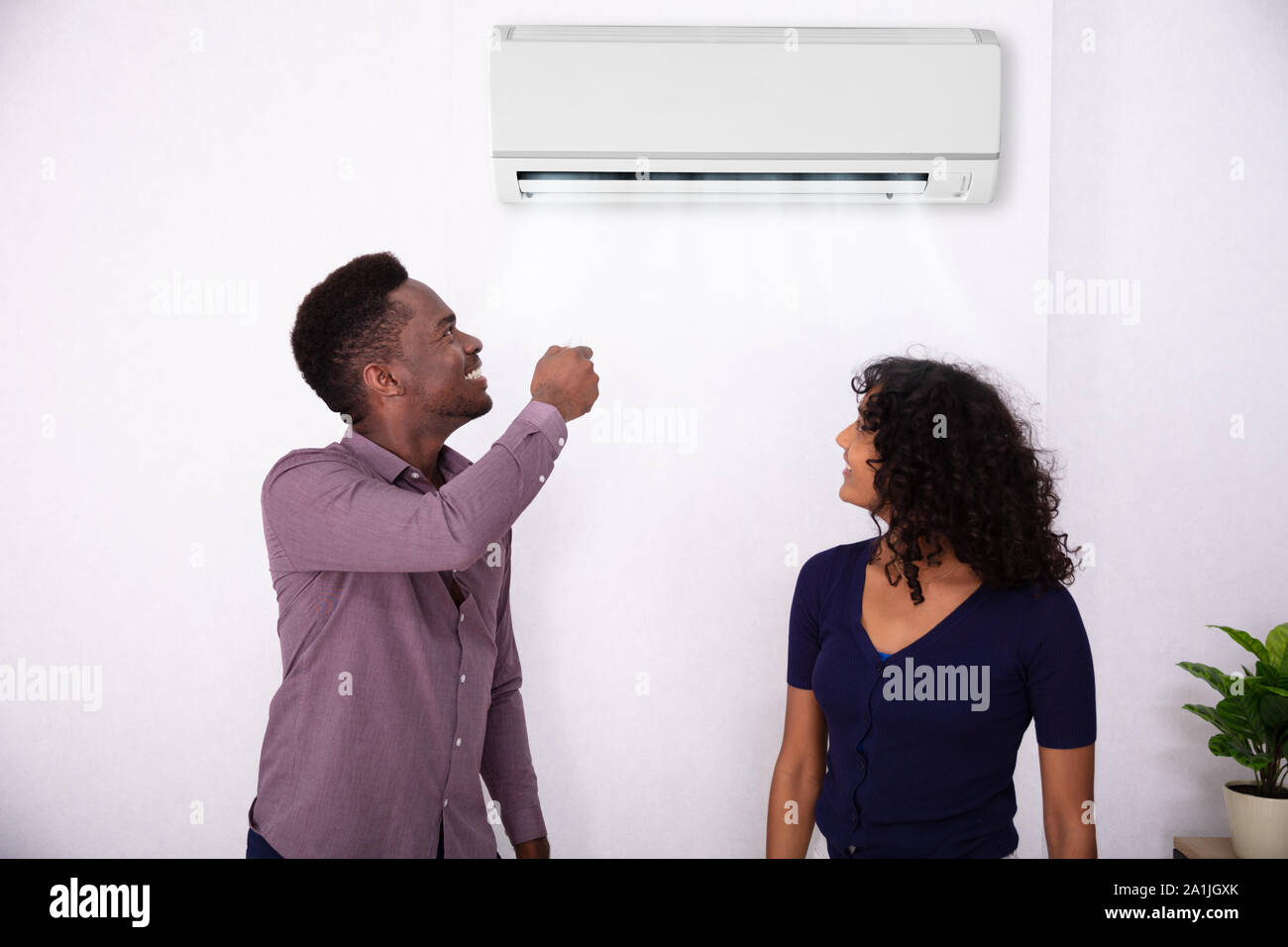 Couple Adjusting Temperature Of Air Conditioner At Home Stock Photo Alamy
