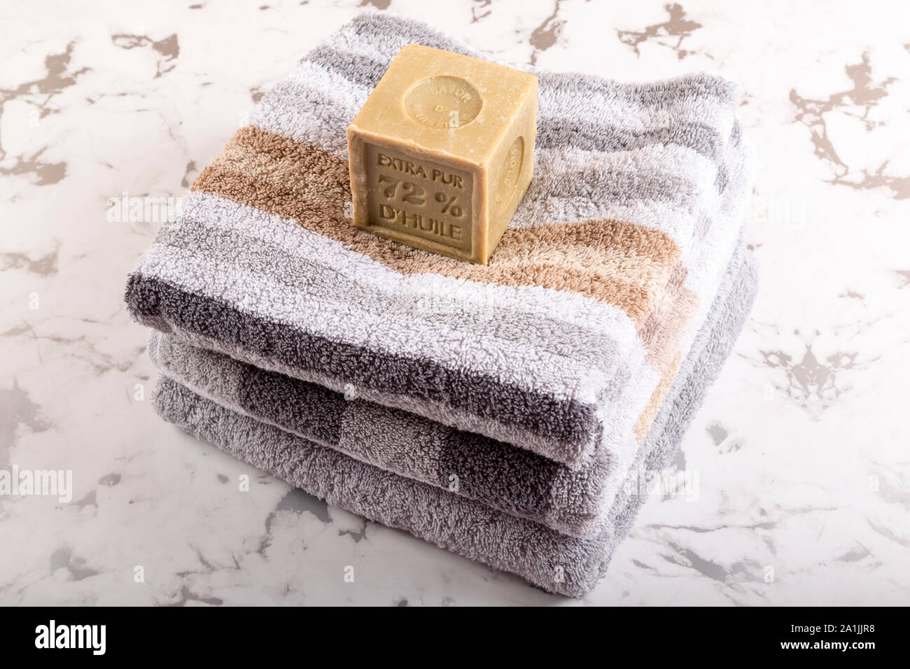 Organic piece of soap on a pile of towels on marble underground. Mood for premium spa, wellness hotel or naturopathy. Stock Photo