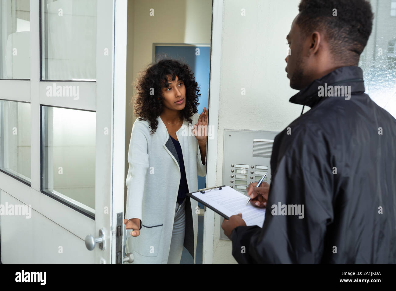 Stressed Woman Opening Door To Bailiff At Home Stock Photo
