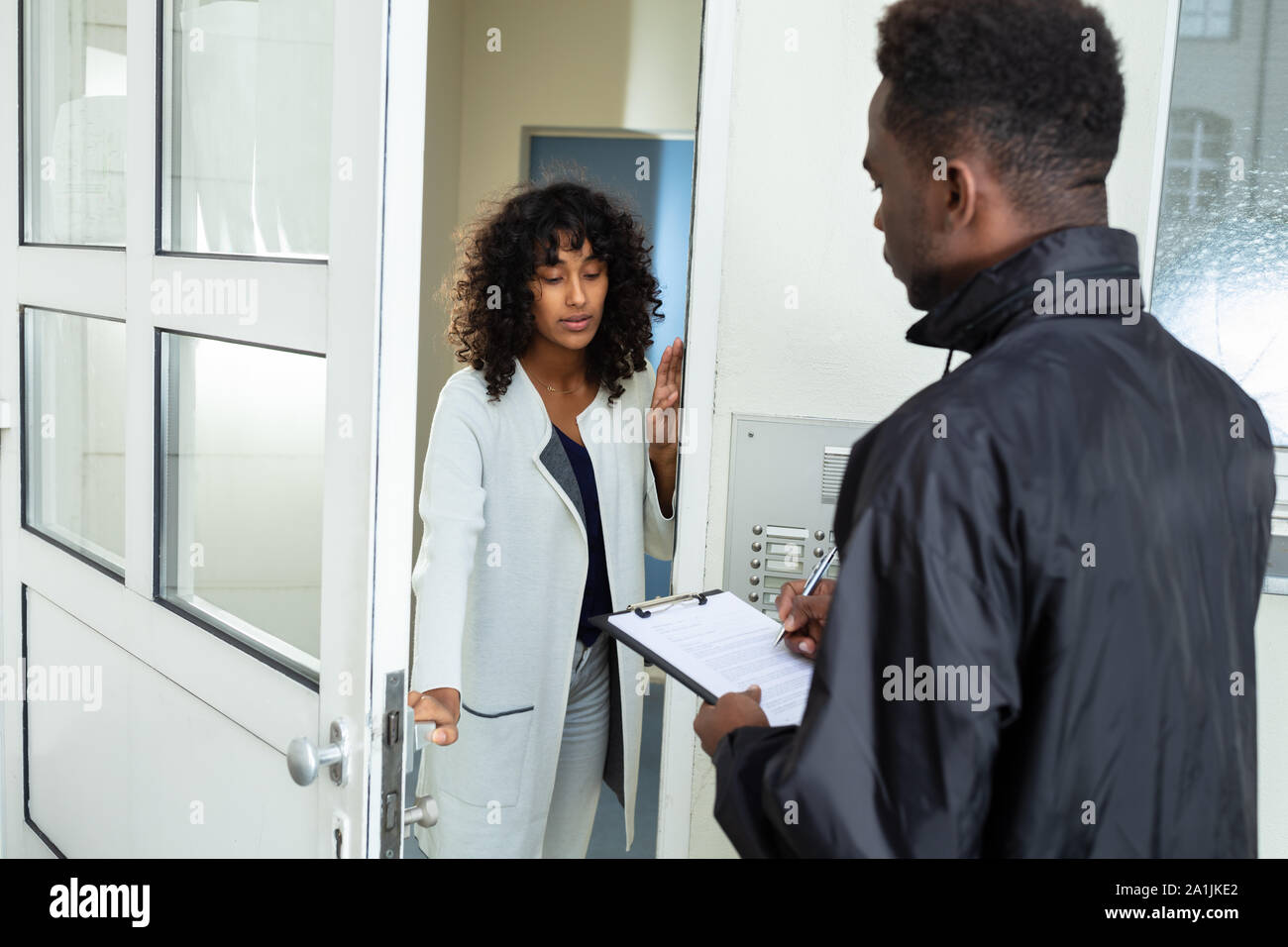 Stressed Woman Opening Door To Bailiff At Home Stock Photo