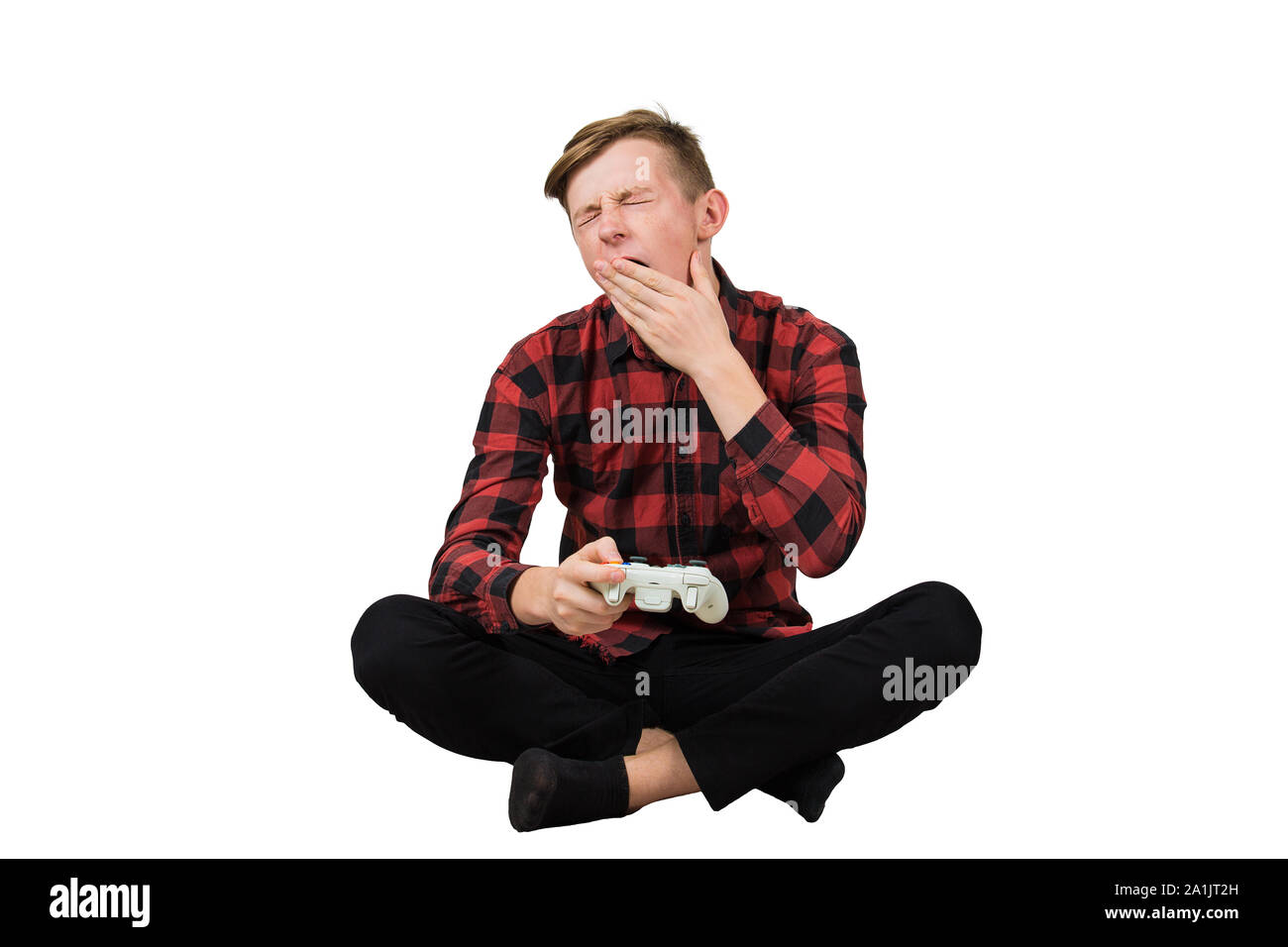 Tired teenage guy seated on the floor playing video games isolated over