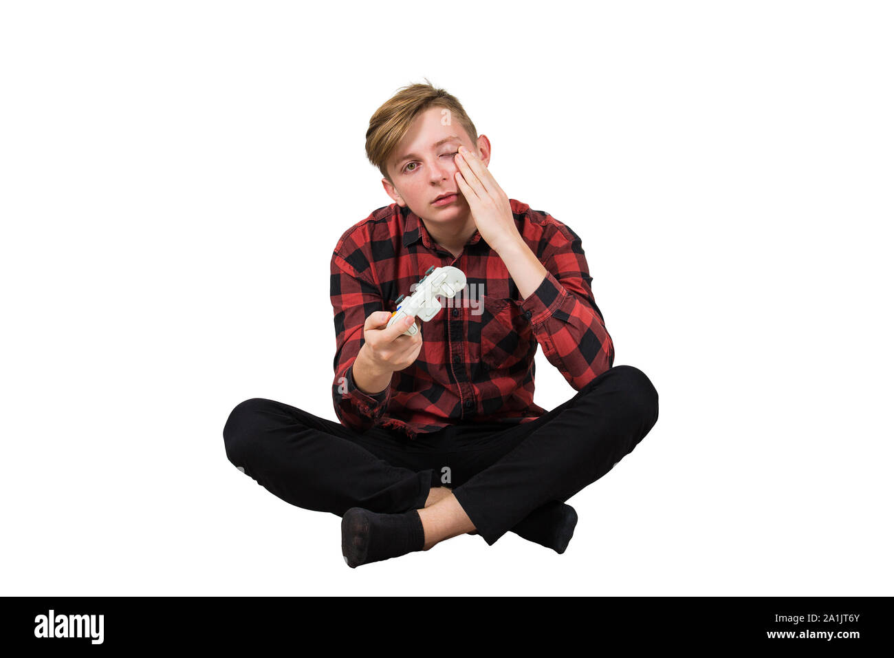 Tired teenage guy seated on the floor playing video games isolated over