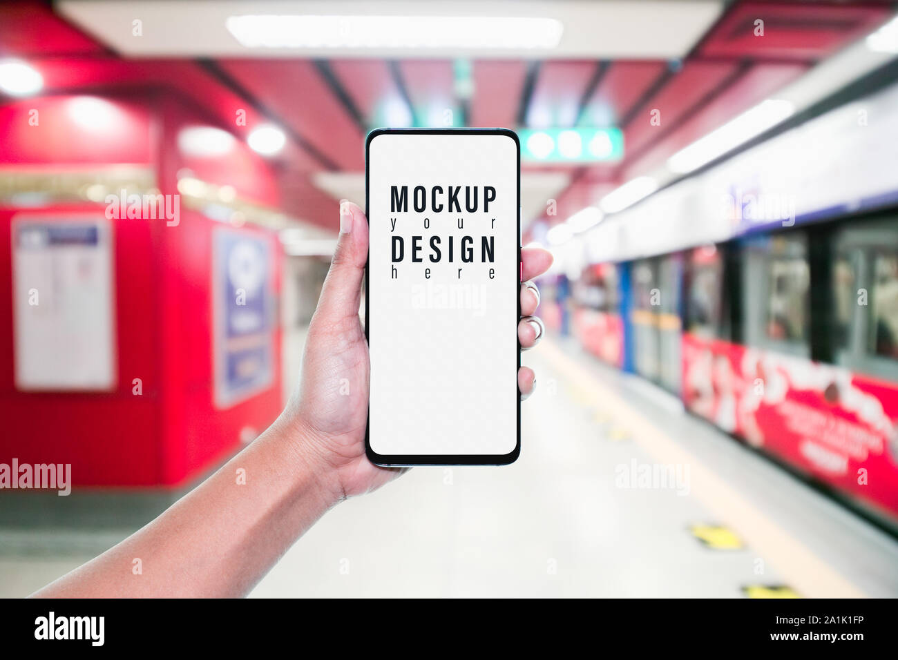 Mockup of hand using mobile phone with copy space blank screen for your advertisement with blurred view of red subway, internet social media technolog Stock Photo