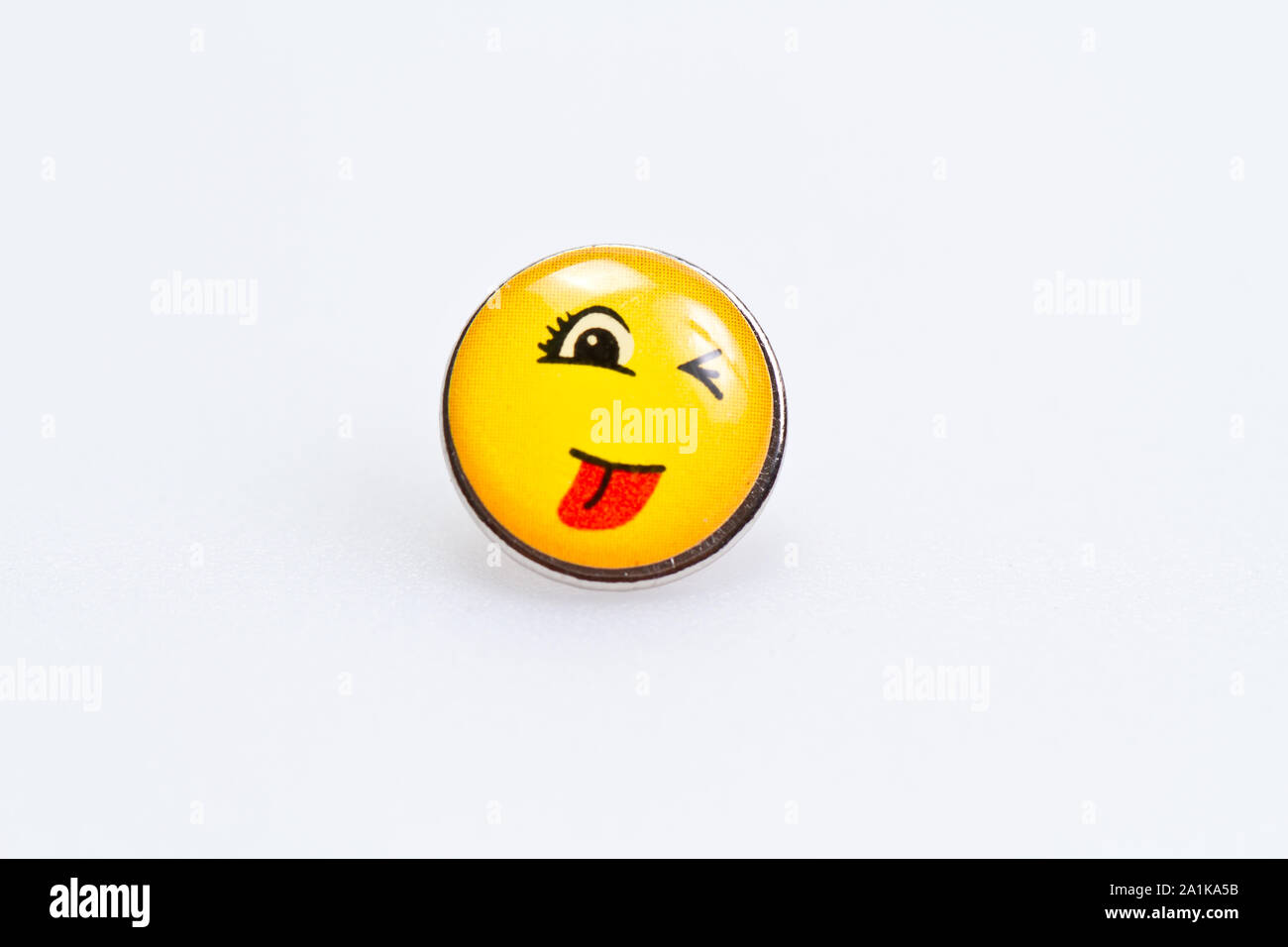 smiley character on metal thumbtack on white surface Stock Photo