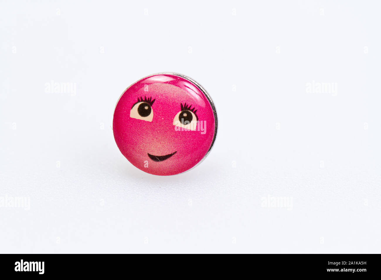 smiley character on metal thumbtack on white surface Stock Photo