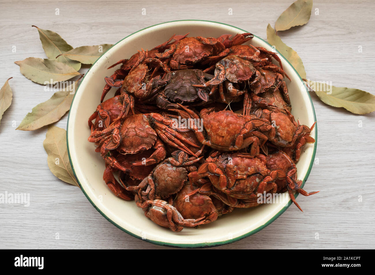 blue crabs cooked in a plate on a wooden table and bay leaves Stock Photo