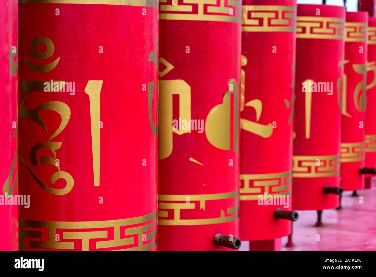 ELISTA, RUSSIA - MAY 5, 2018: Close up row of red buddhist prayer wheels with golden text on them. Elista is the capital of Kalmykia Republic with 103 Stock Photo