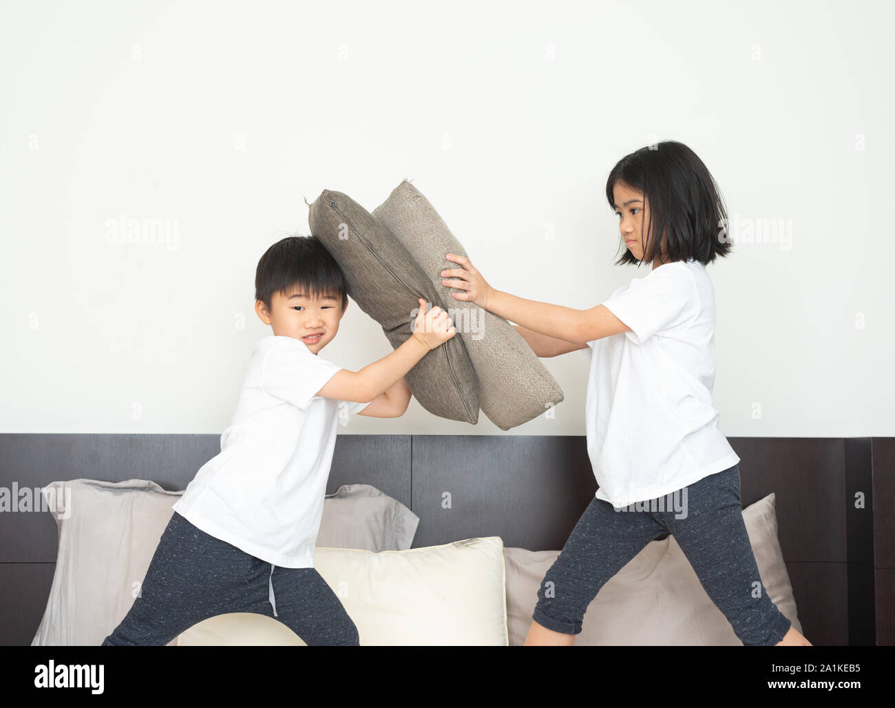 Boys And Girls In Pajamas Are Fighting Each Other With Pillows