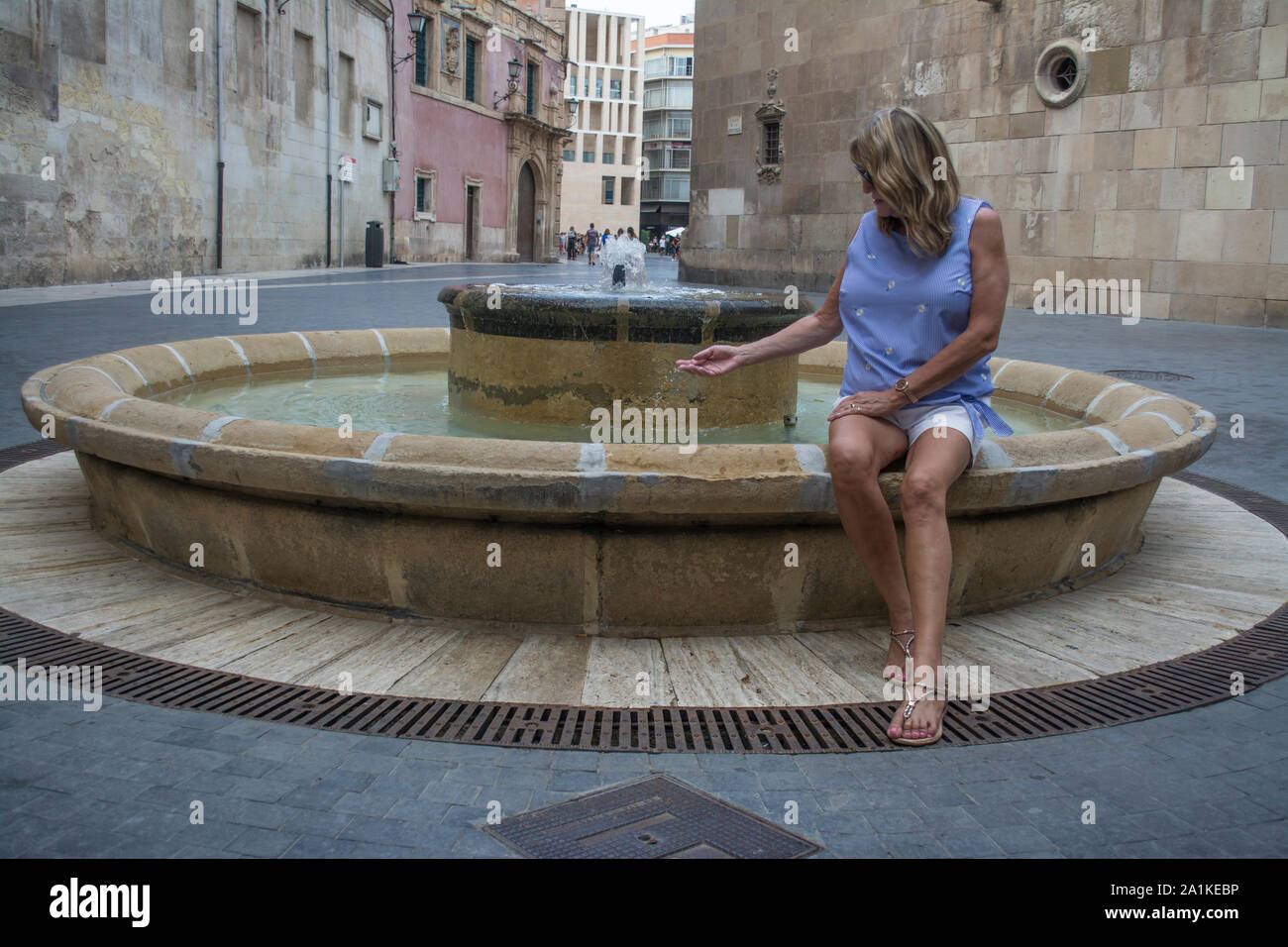 Female tourist dips her hand in a water fountain in the City of Murcia Spain Stock Photo