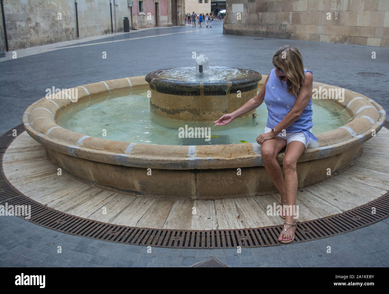 Female tourist dips her hand in a water fountain in the City of Murcia Spain Stock Photo