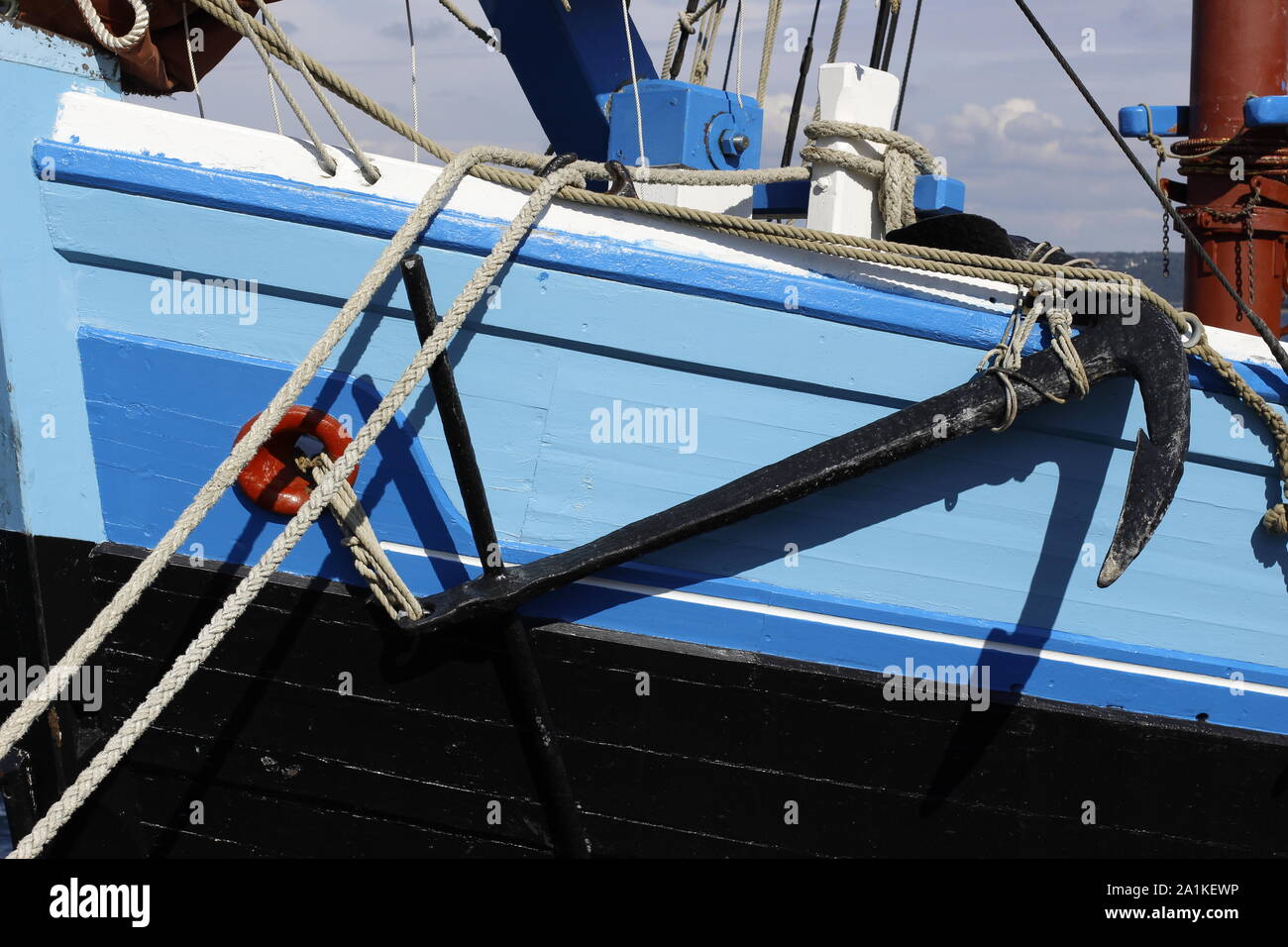 detail of a large blue wooden fishing boat showing rigging, mast and anchor Stock Photo