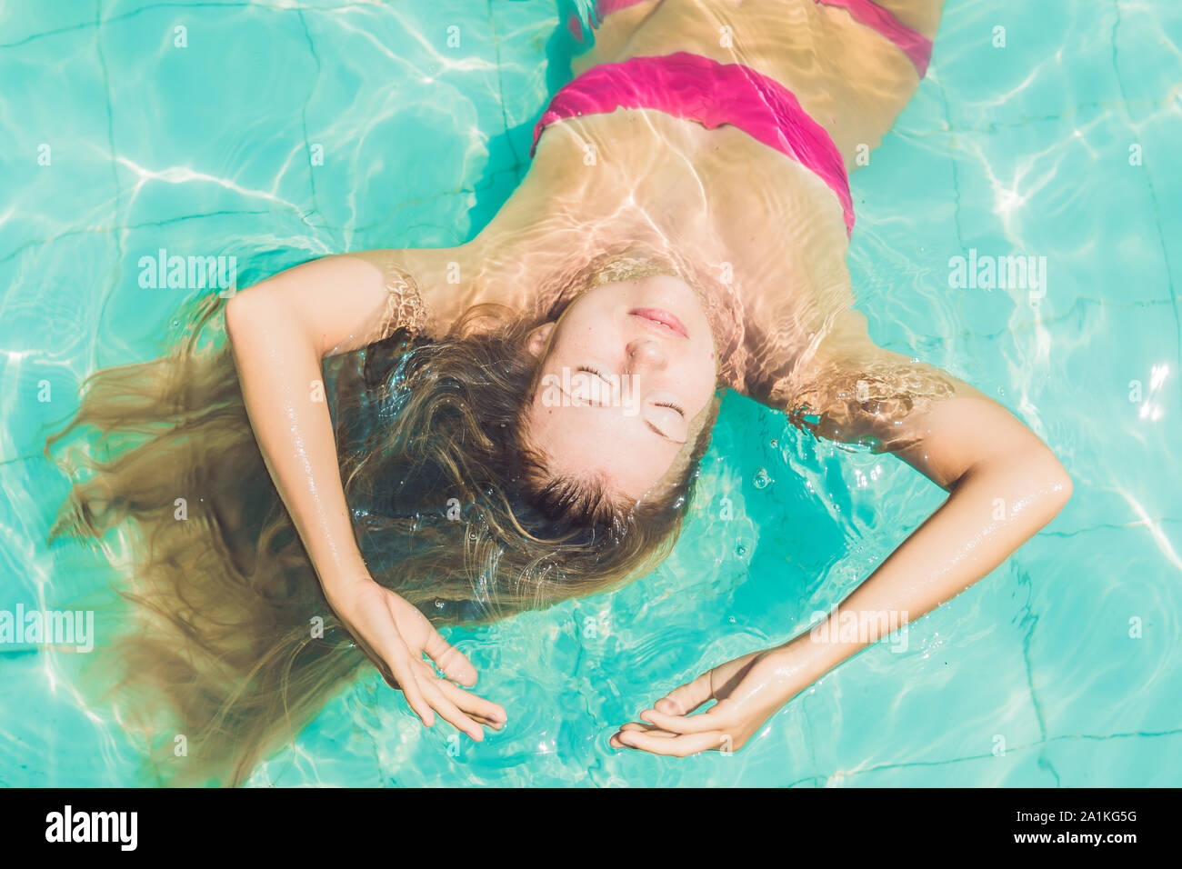 Beautiful young woman floating in pool relaxing Top view. Holiday ...