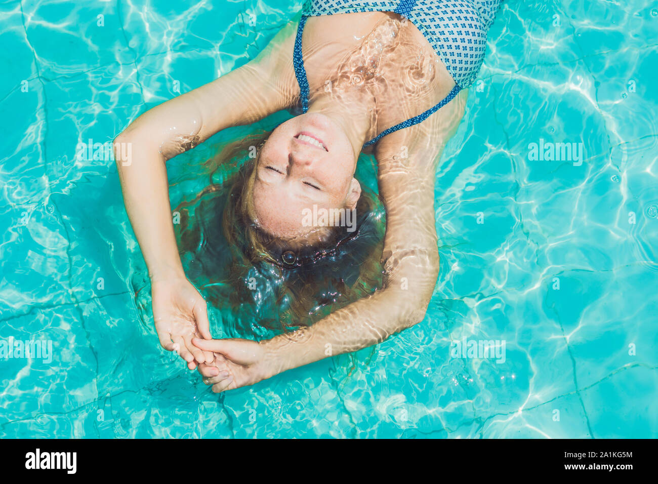 Woman Floating In Pool Beautiful young woman floating in pool relaxing Top view. Holiday ...