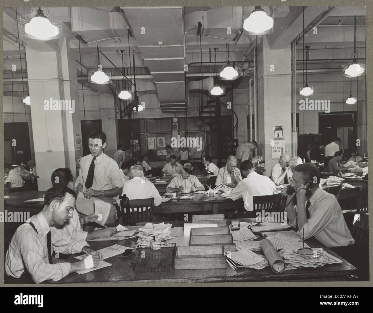 News room of the New York Times newspaper Right foreground, city editor.; News room of the New York Times newspaper Right foreground, city editor. Two assistants, left foreground. City copy desk in middle ground, with foreign desk, to right; telegraph desk to left. Make-up desk in center back with spiral staircase leading to composing room. Copy readers go up there to check proofs.; Stock Photo