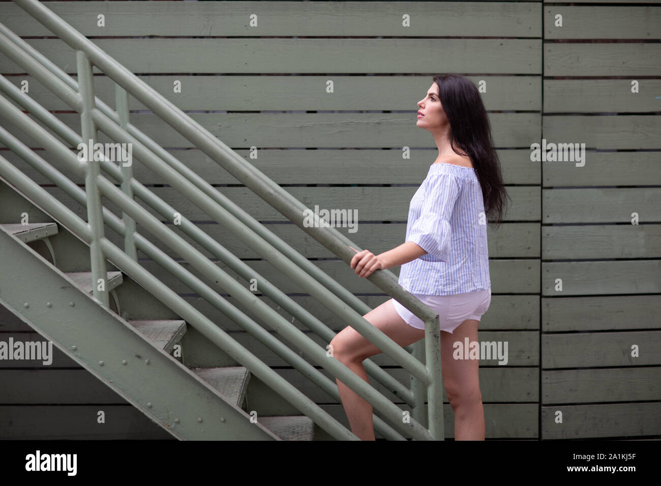 Beautiful young woman climbing industrial stairs on the backstreet Stock Photo Alamy