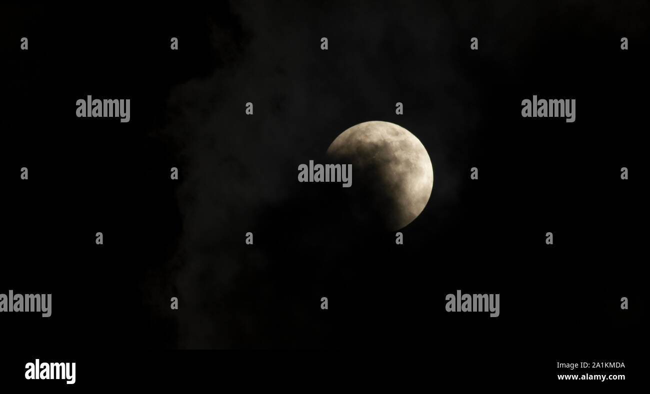 Total lunar eclipse in progress with scary clouds Stock Photo