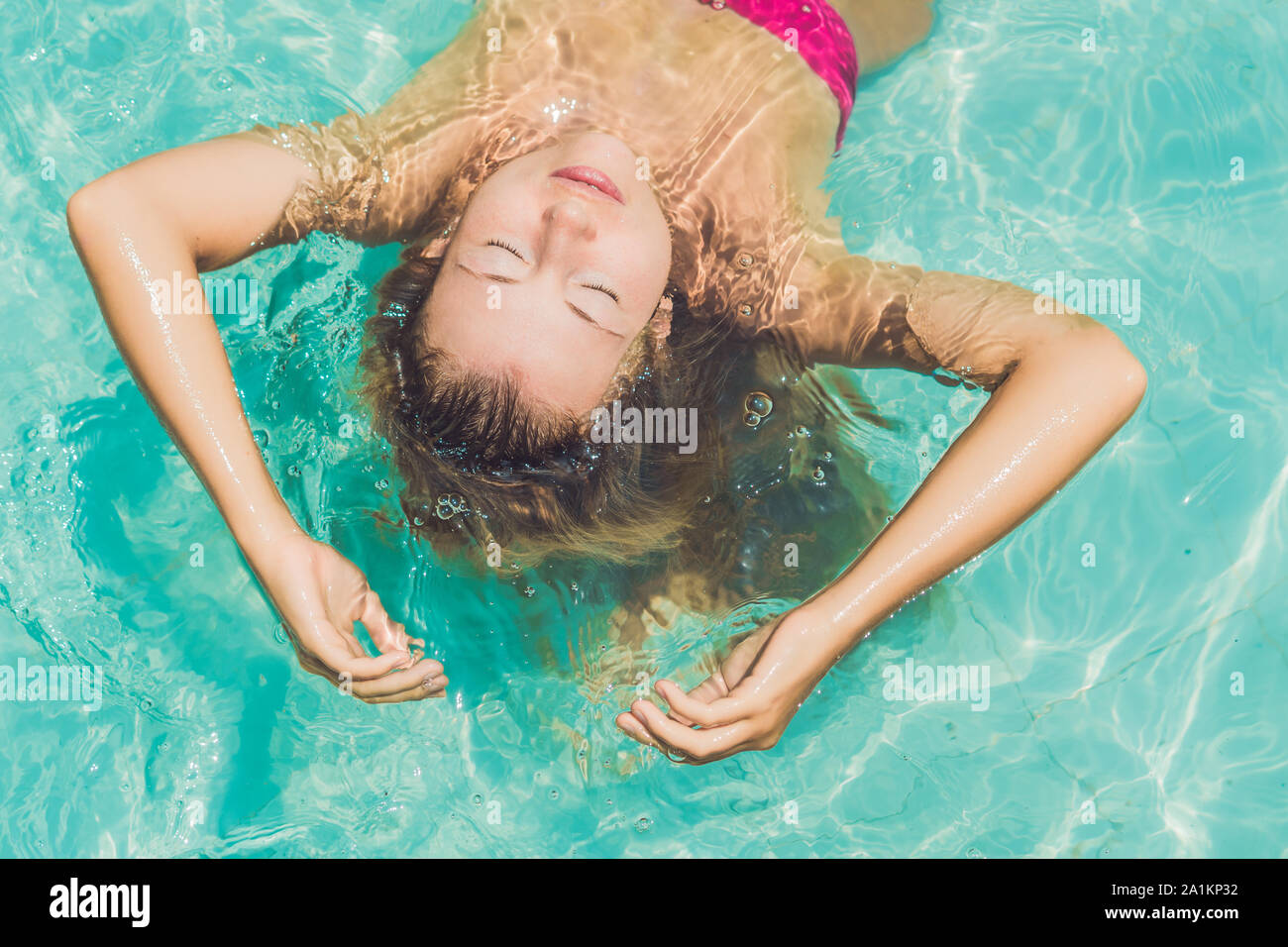 Woman Floating In Pool Beautiful young woman floating in pool relaxing Top view. Holiday ...