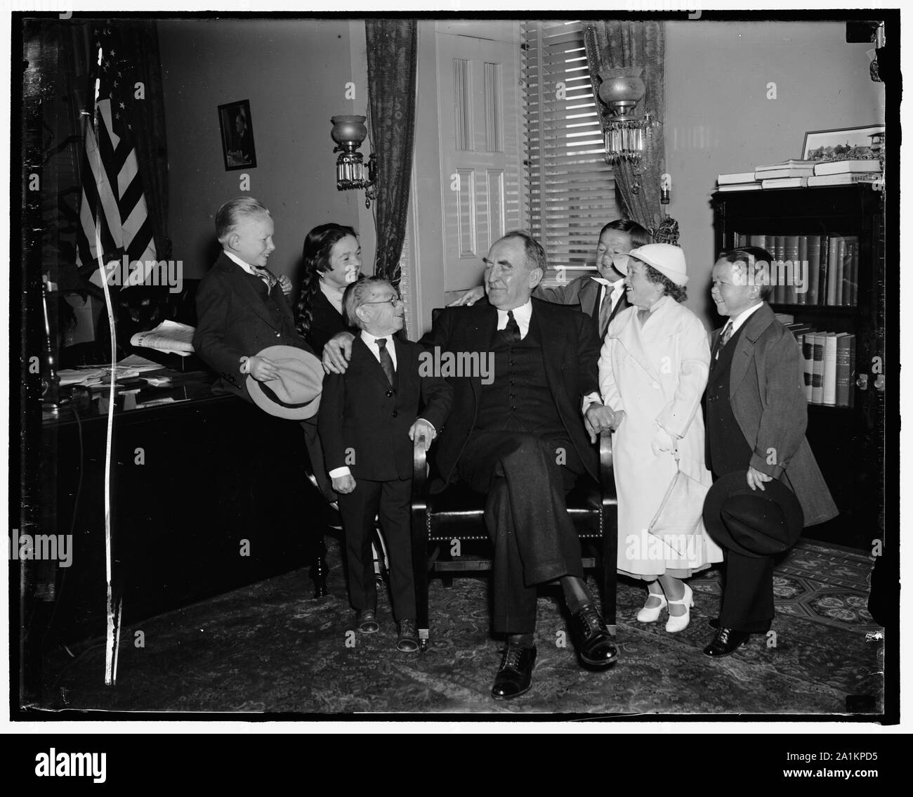 No midget lap-sitting for Speaker Bankhead. Washington, D.C., April 30. Lap-sitting is out Speaker Bankhead today as he greeted a troupe of circus midgets from his home state of Alabama [at the] Capitol. An enterprising photographer sought to repeat the J.P. Morgan act of a few years ago (?) the noted financier placed on the midgets on [his] lap at a Senate hearing. But it was no go today as the Speaker was concerned, 4/30/37 Stock Photo