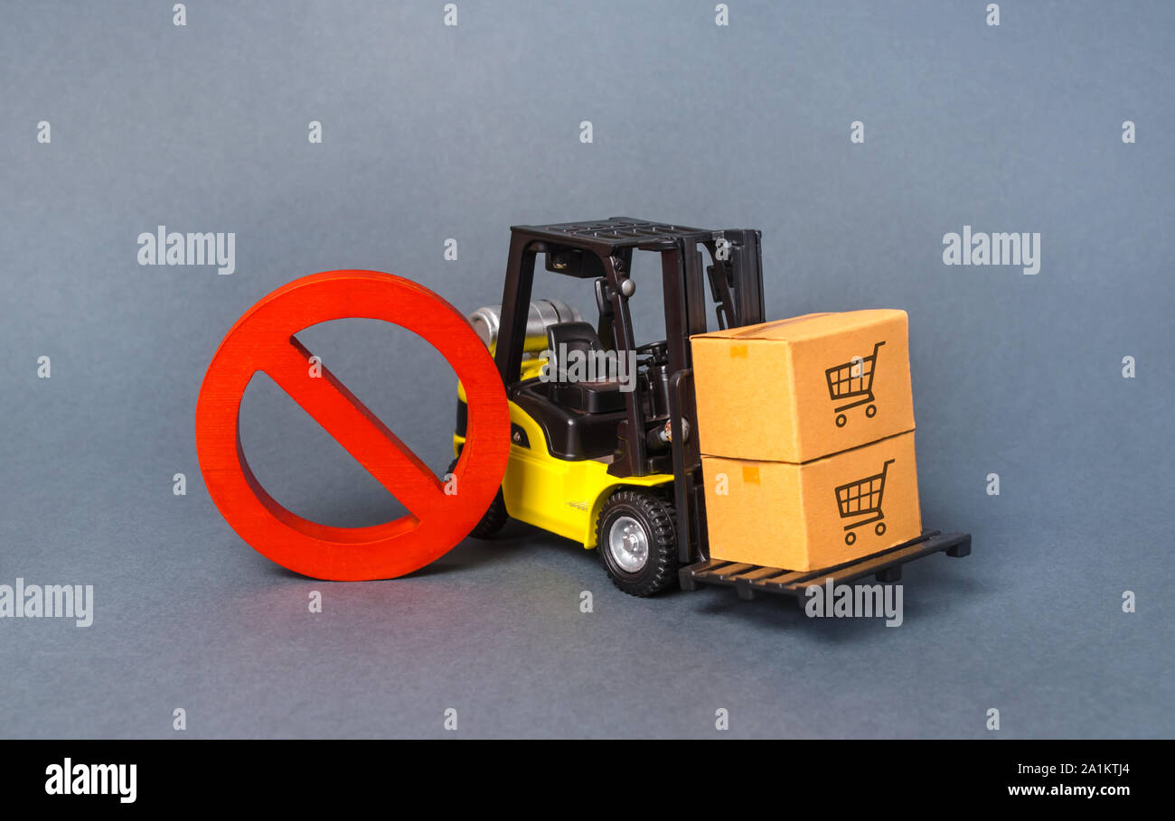 Yellow Forklift truck carries boxex and a red prohibition symbol NO. Embargo trade wars. Restriction on importation production, ban on export of dual- Stock Photo