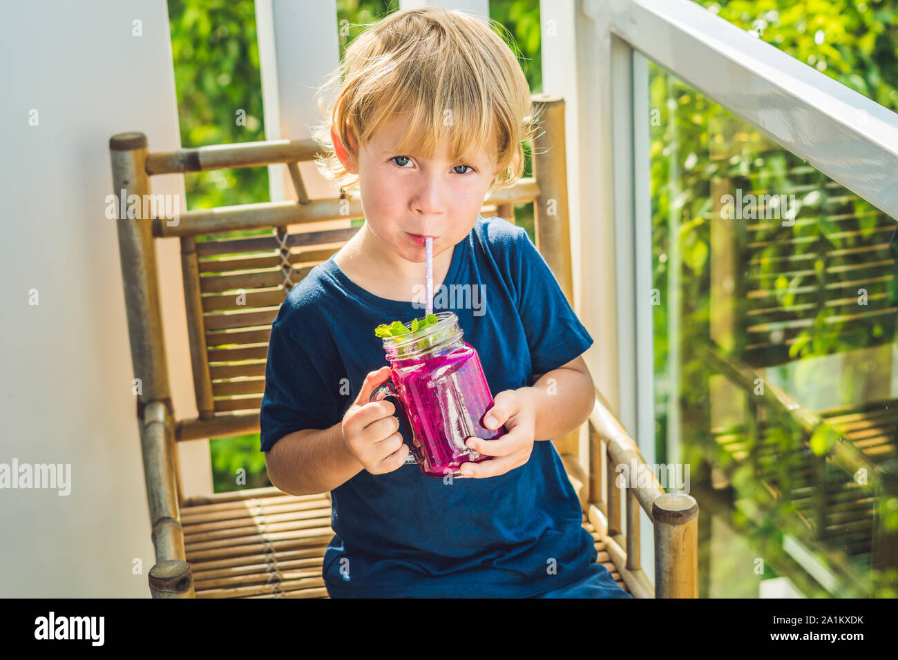 The boy holds smoothies from a dragon fruit with a mint leaf and a drinking straw Stock Photo
