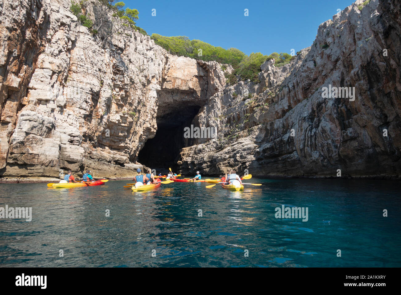 Croatia tourism; Tourists kayaking into sea caves, Dalmatian Coast of southern Croatia Europe Stock Photo