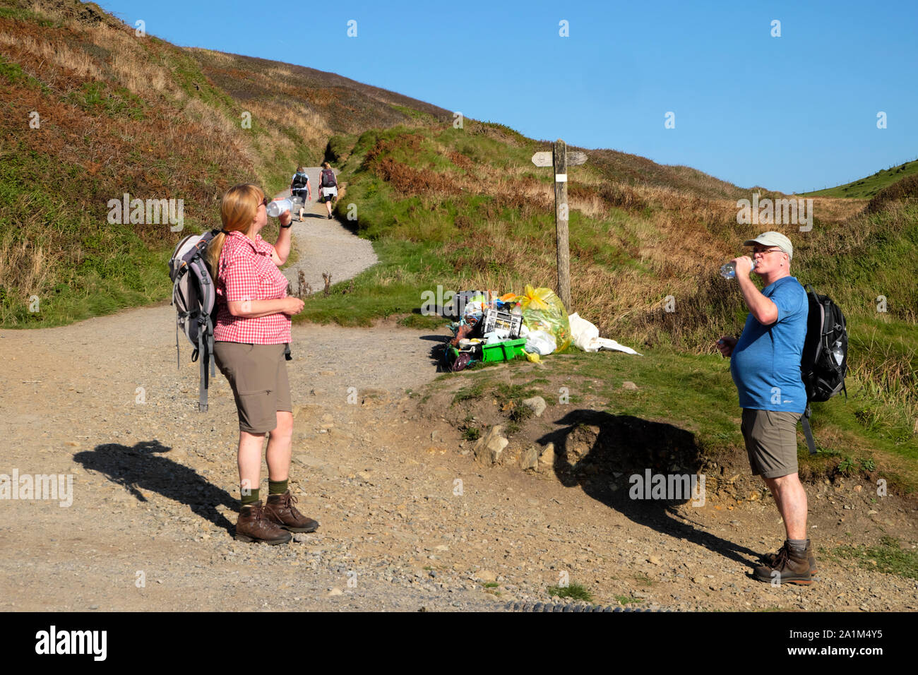 Walkers drinking water from plastic bottles & rubbish collection collected from the beach at Marloes Wales Coastal Path Pembrokeshire UK  KATHY DEWITT Stock Photo